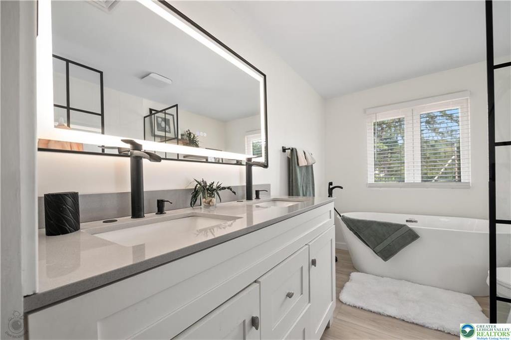 Bathroom with double vanity, freestanding tub, and LED mirror