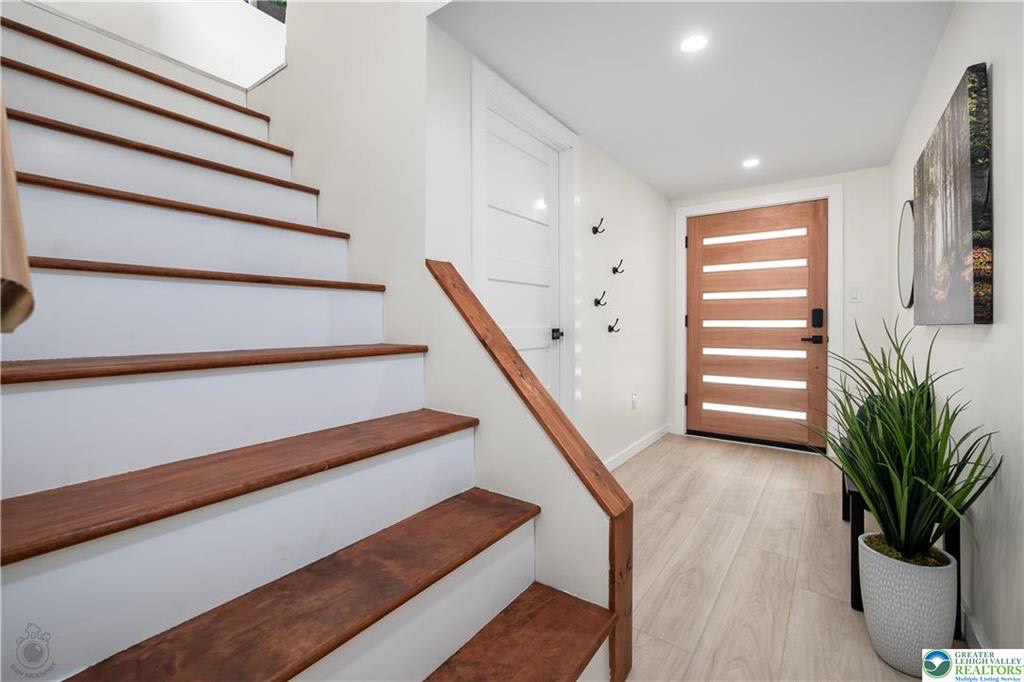 Entry foyer with wood-tread staircase and modern front door
