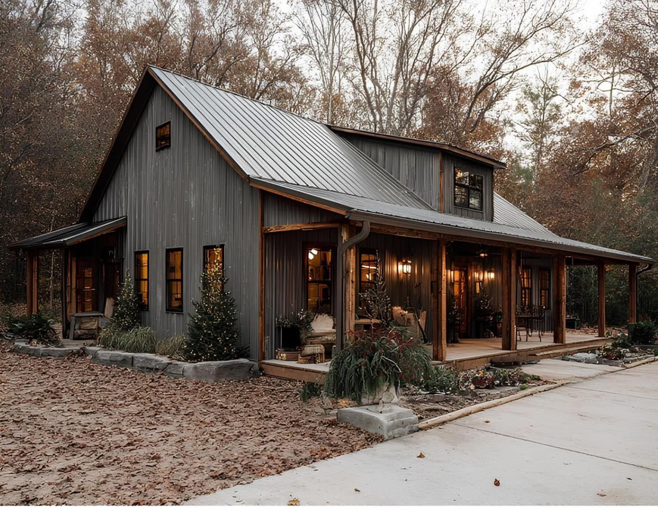 Gray board-and-batten barndominium with a wraparound porch nestled in the woods