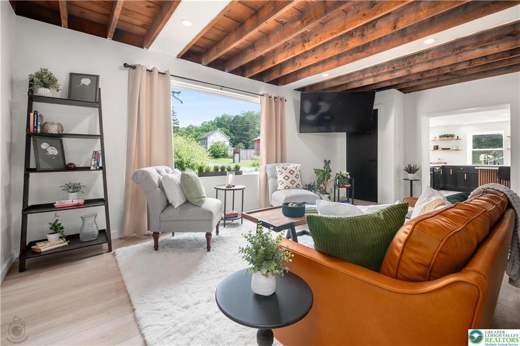 Bright living space with exposed beam ceiling and large picture window